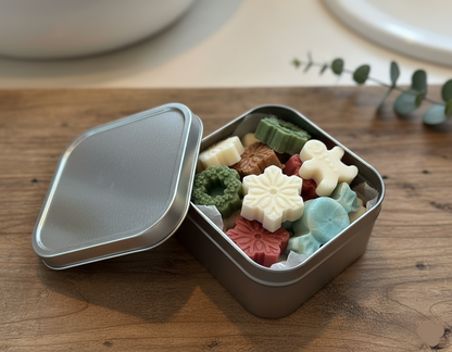 Holiday soap tin with mini guest soaps shaped like snowflakes, bells, and gingerbread men